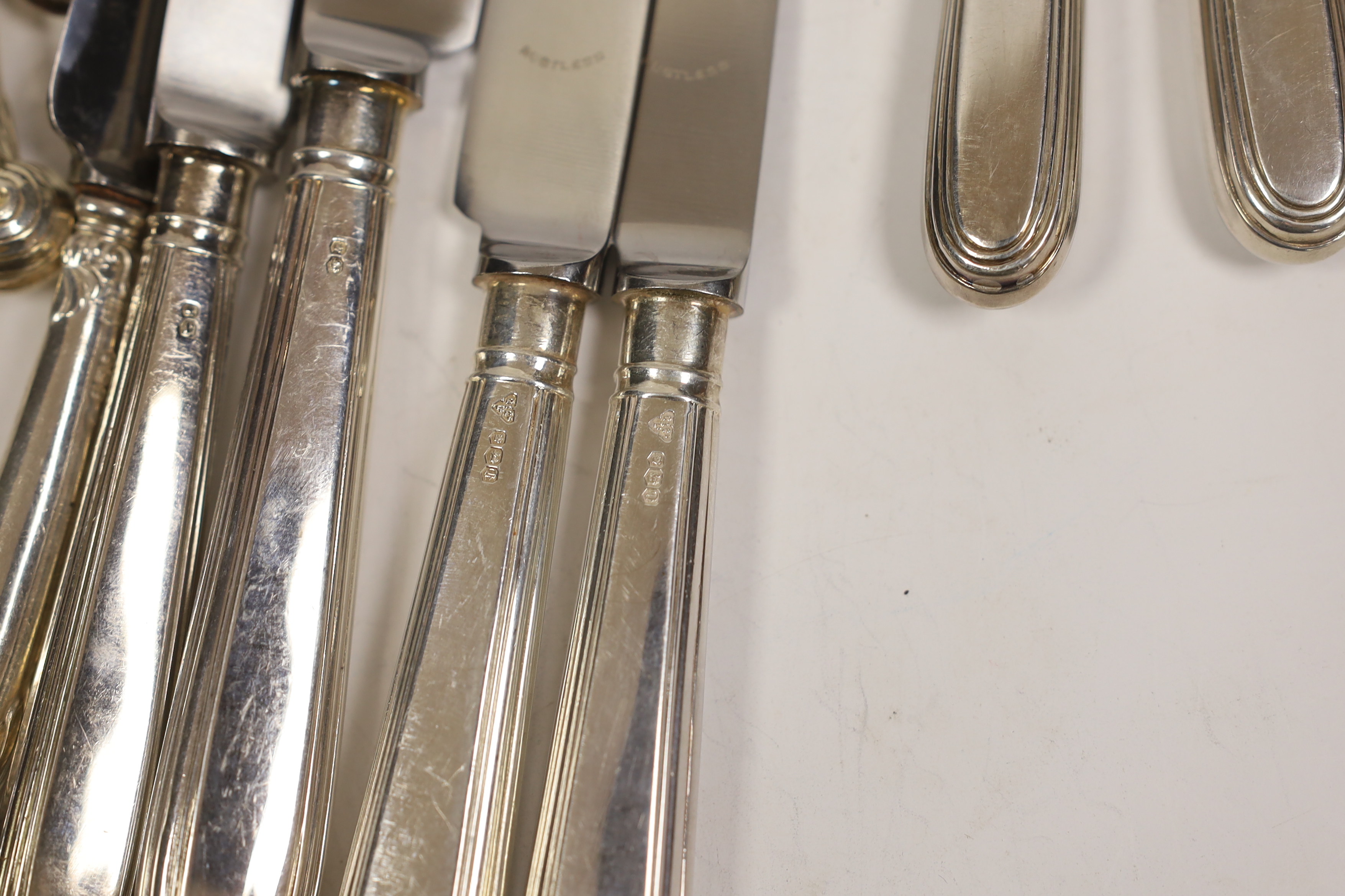 A set of six modern silver handled dessert knives and six table knives, Garrard & Co Sheffield, 1974, a set of six silver pistol handled tea knives and a silver plated 'Humpty Dumpty' child's rattle(a.f.).